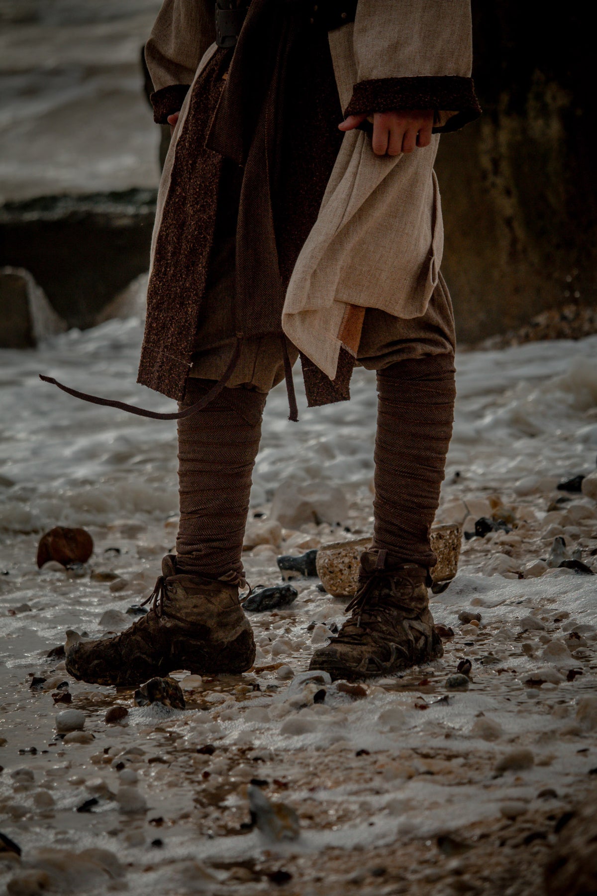 Brown herringbone wool leg wraps for LARP, worn over muddy boots.