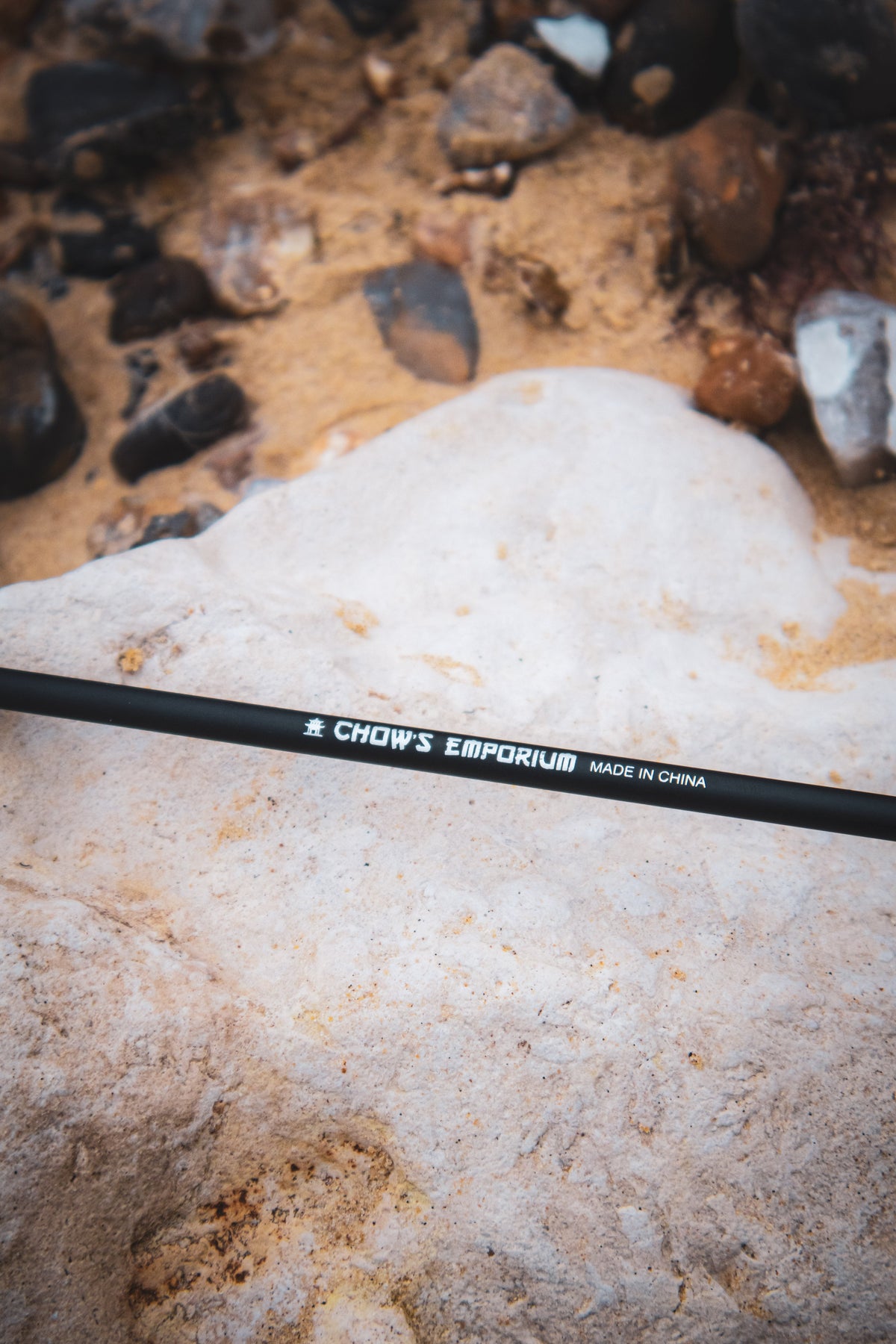 Black arrow with visible brand name on a sandy and rocky surface.