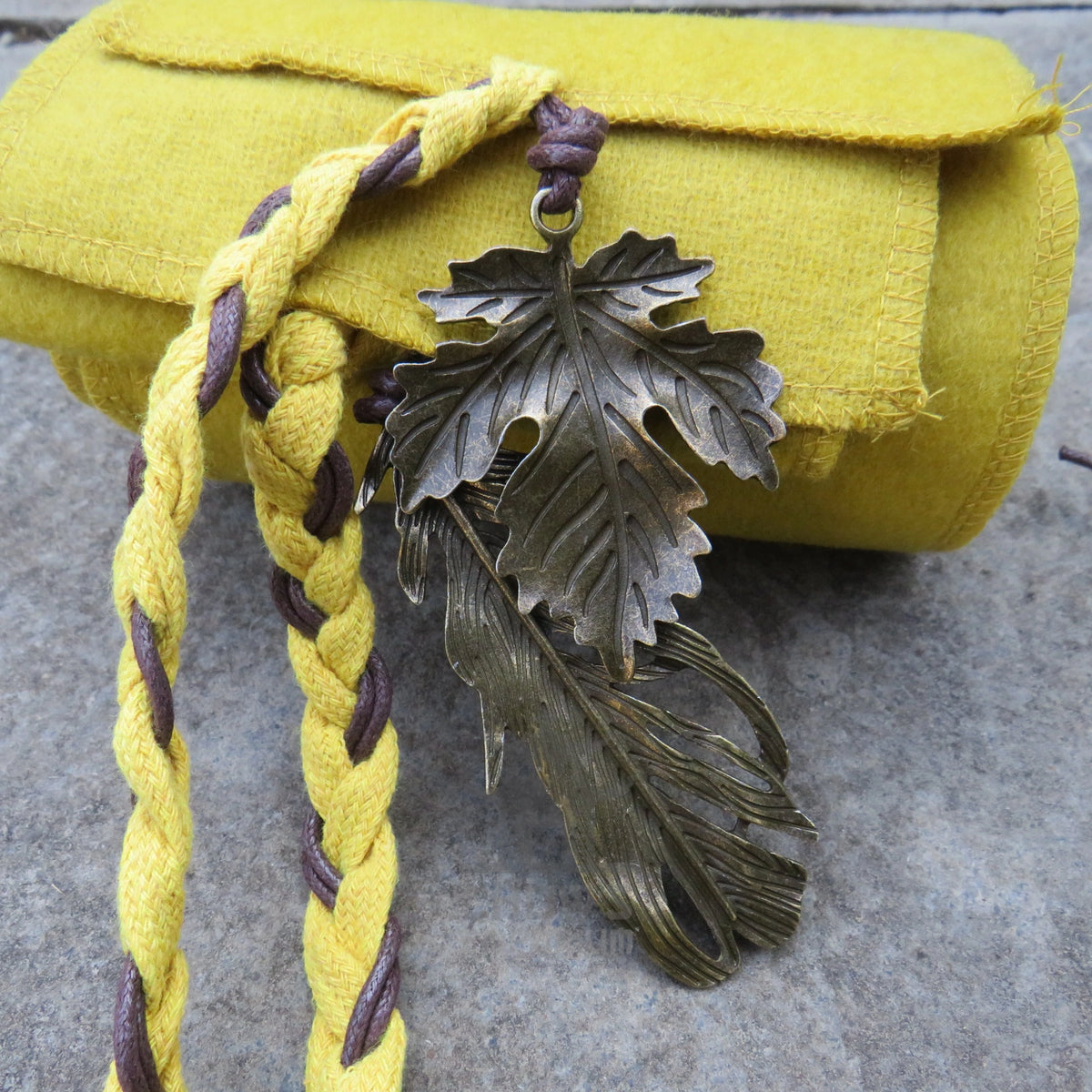 Leather-look cord and metal charm on the end of the ochre sash
