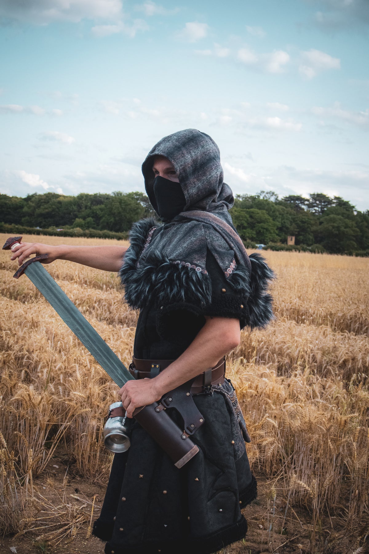 Medieval LARP costume side view featuring a black faux leather tunic and wool wrap around hood.