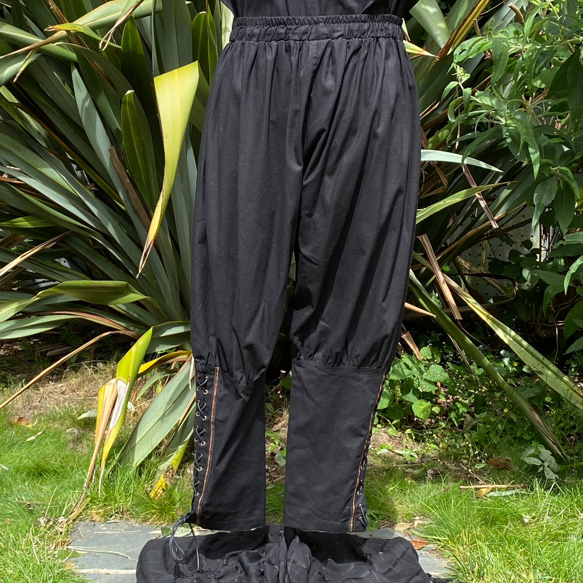 Black Viking pants with side lacing in a garden setting, for LARP events.