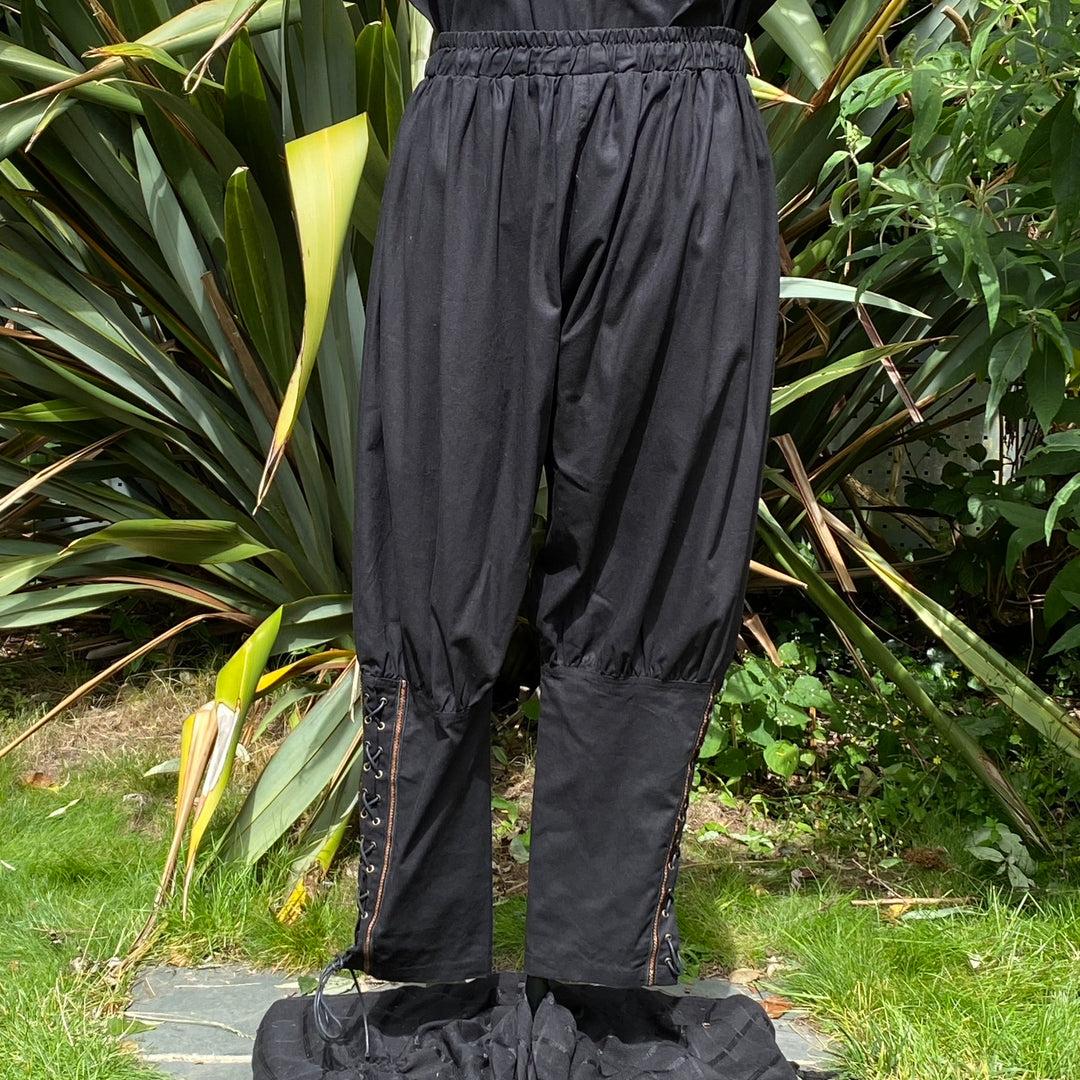 Black Viking pants with side lacing in a garden setting, for LARP events.