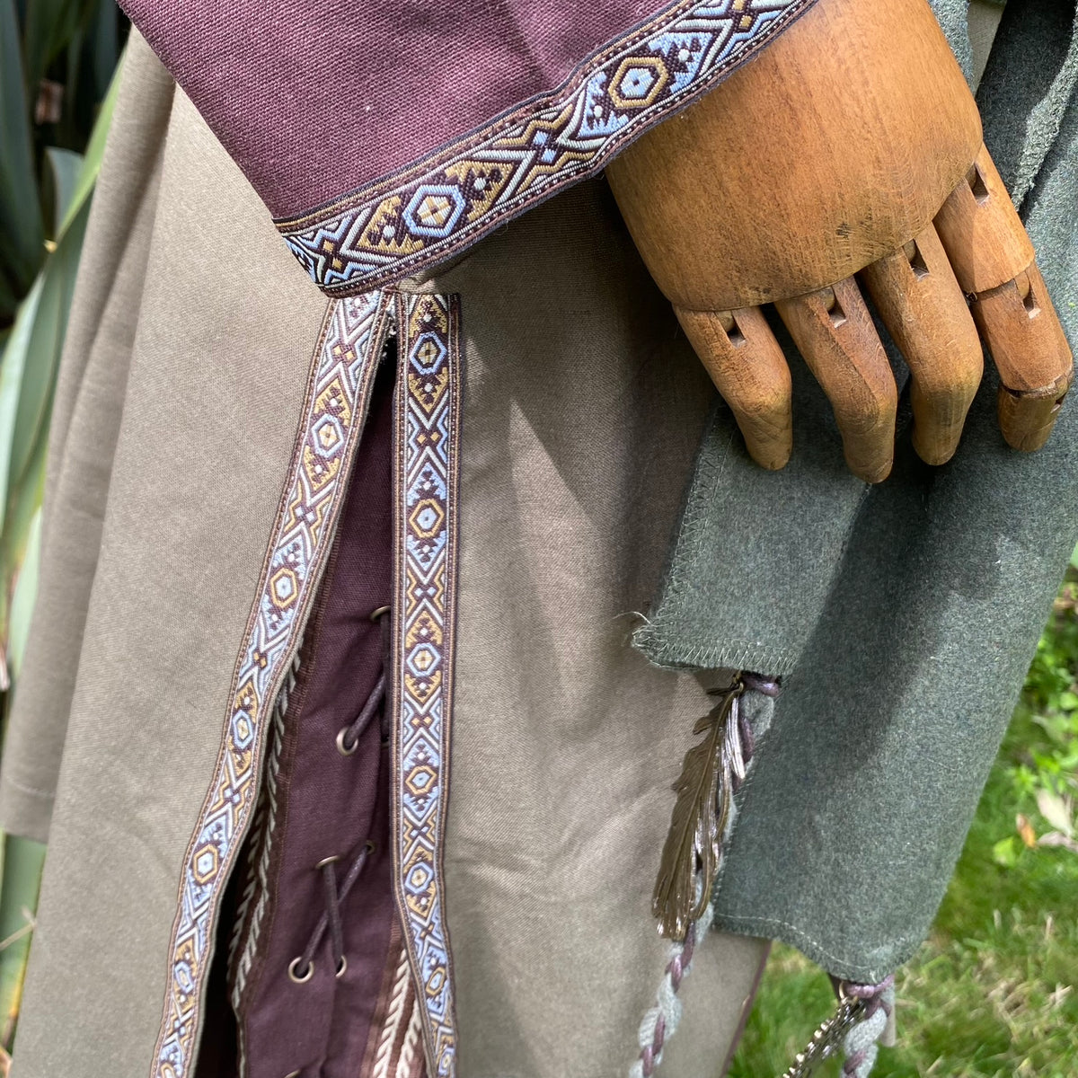 Embroidered sleeve detail on medieval LARP tunic with wooden hand mannequin.