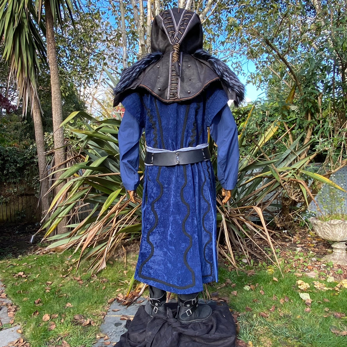 Back view of blue medieval LARP costume with black ornate hood and fur trim.