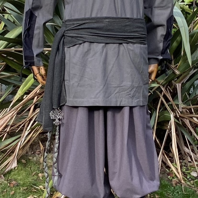 Back view of LARP outfit with tree pendant, loose pants, and medieval sash.