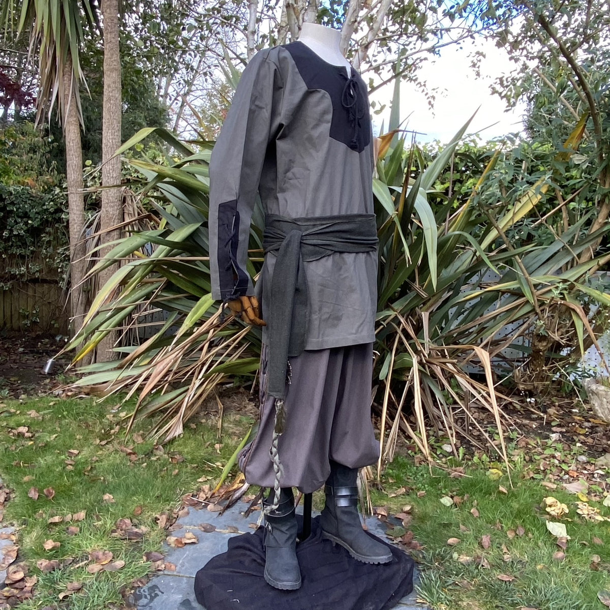 Mannequin in medieval LARP outfit, side view, green shirt and sash.