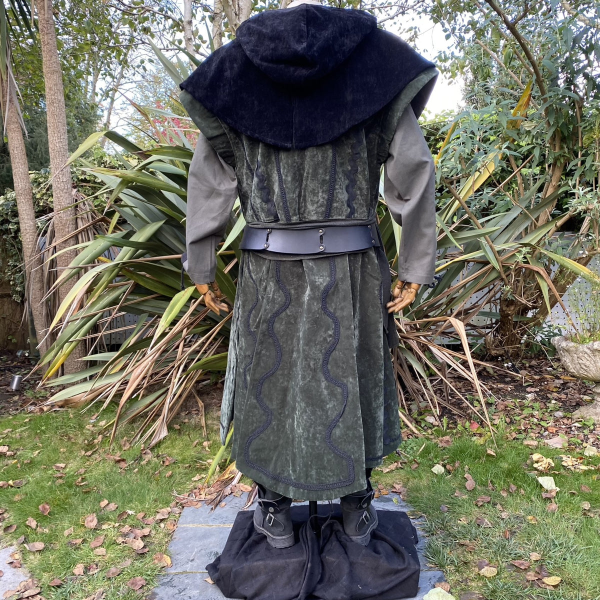 Back view of green medieval LARP waistcoat with black hood and wavy trim.