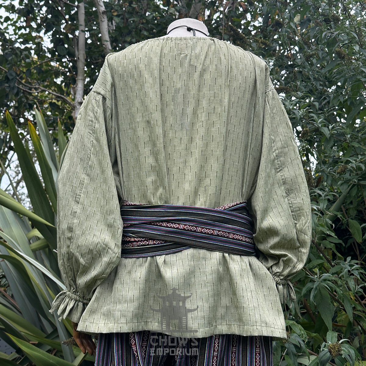 Rear view of green medieval LARP shirt with striped sash and pants.