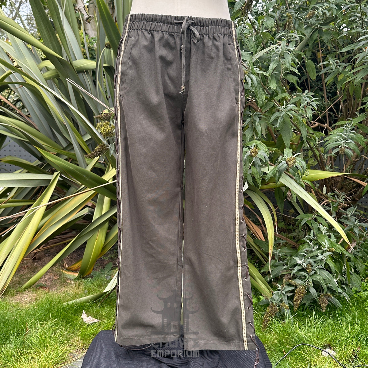 Medieval LARP pants in garden setting with side lace visible.