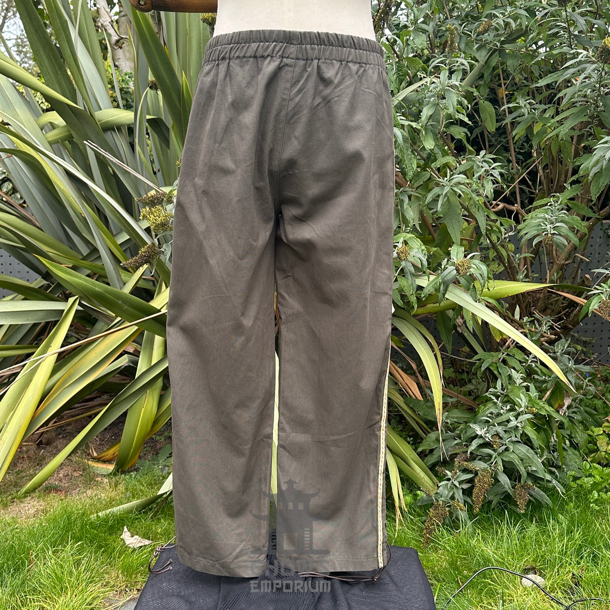 Back view of medieval straight-leg trousers in grey cotton with relaxed unisex fit no boots.