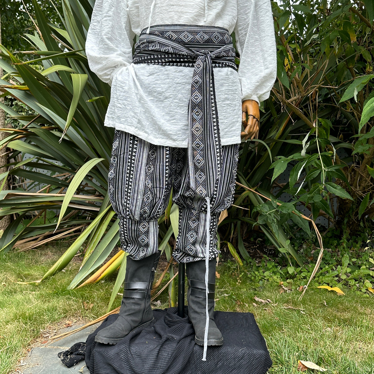 Medieval LARP outfit front view, featuring black and white patterned trousers and matching sash.