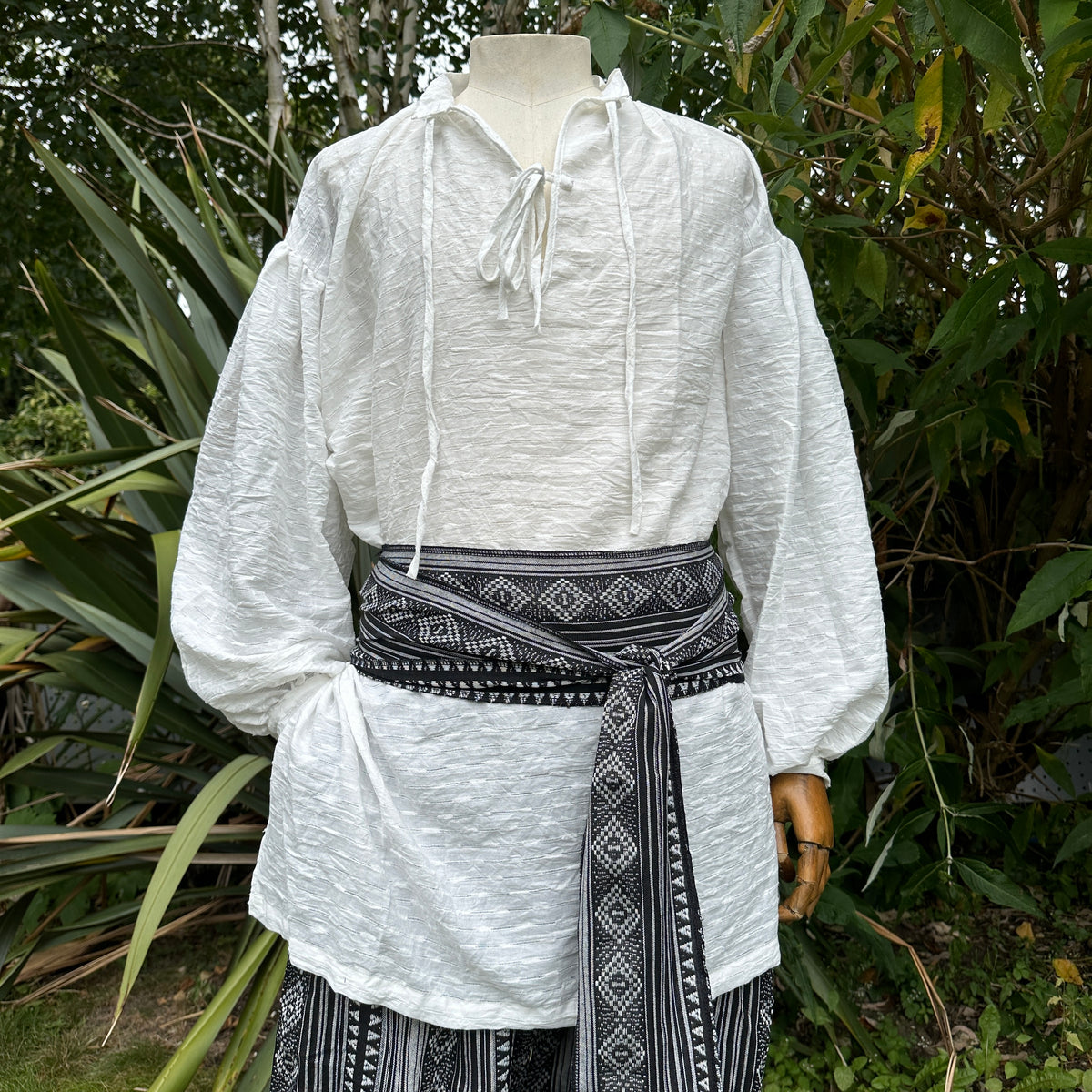 White medieval LARP shirt with black patterned sash.