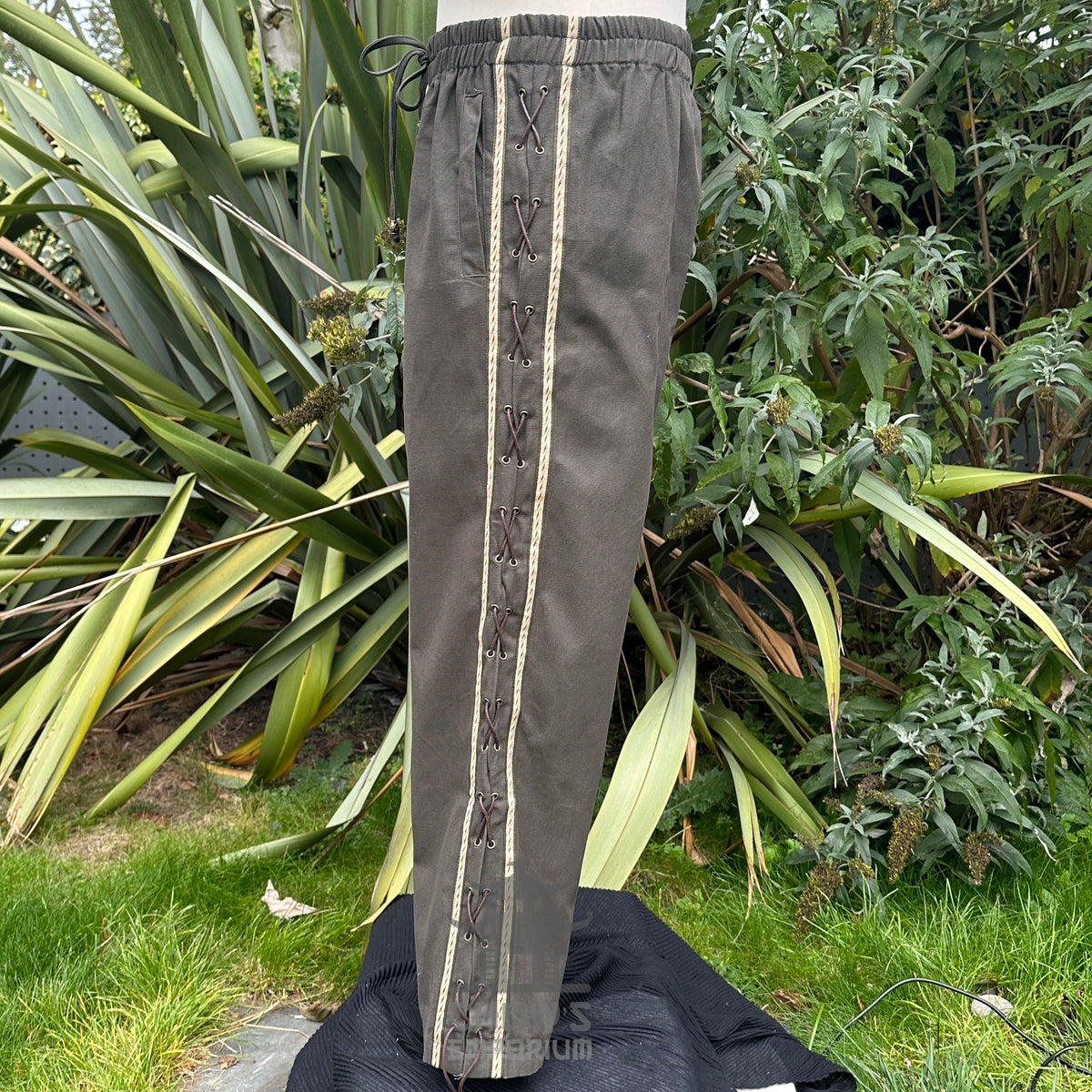 Medieval LARP pants with side view lace-up next to greenery.