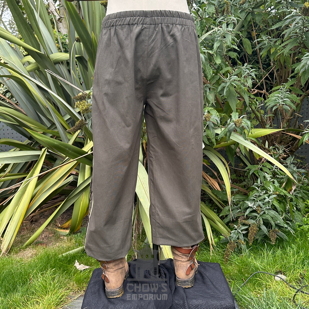 Back view of medieval straight-leg trousers in grey cotton with relaxed unisex fit.