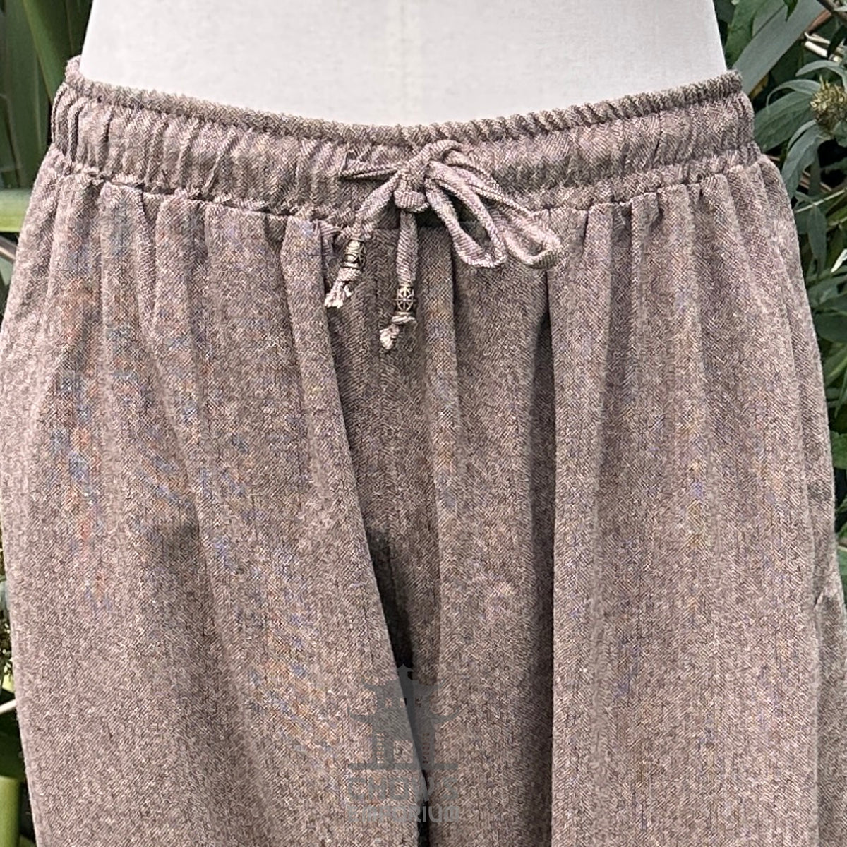 close up of drawstring detail on brown wool pants.