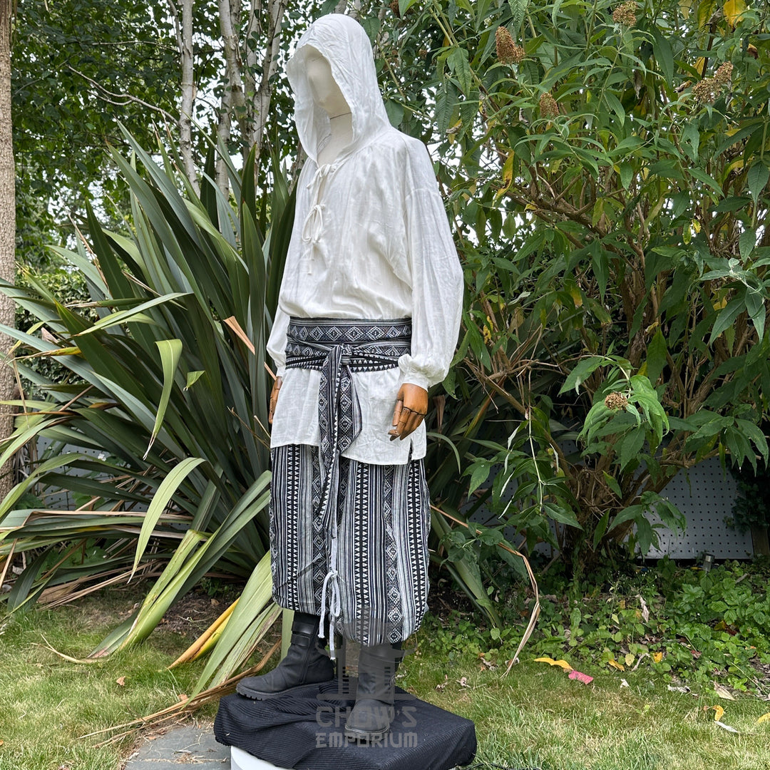 Medieval LARP outfit side view, featuring a white hooded shirt, black and white trousers and sash.