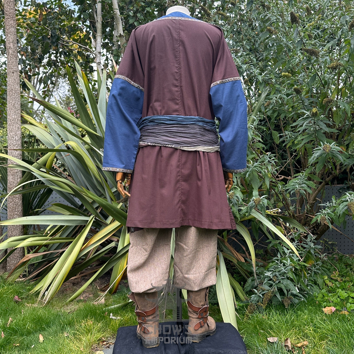 LARP medieval outfit with brown tunic, blue sleeves, trousers, and sash, rear view.