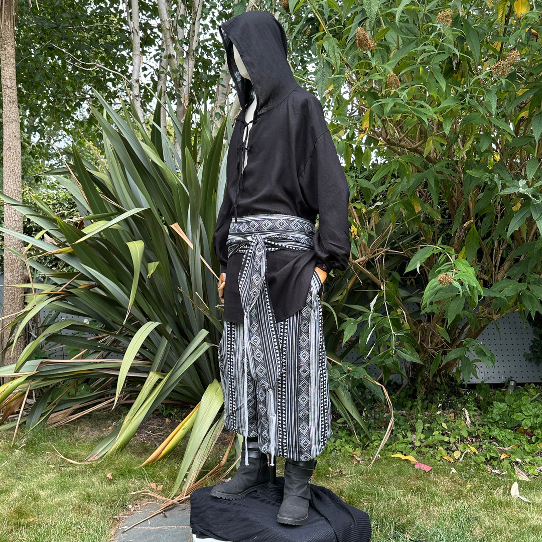 Medieval LARP outfit side view, featuring a black hooded shirt, black and white trousers and.