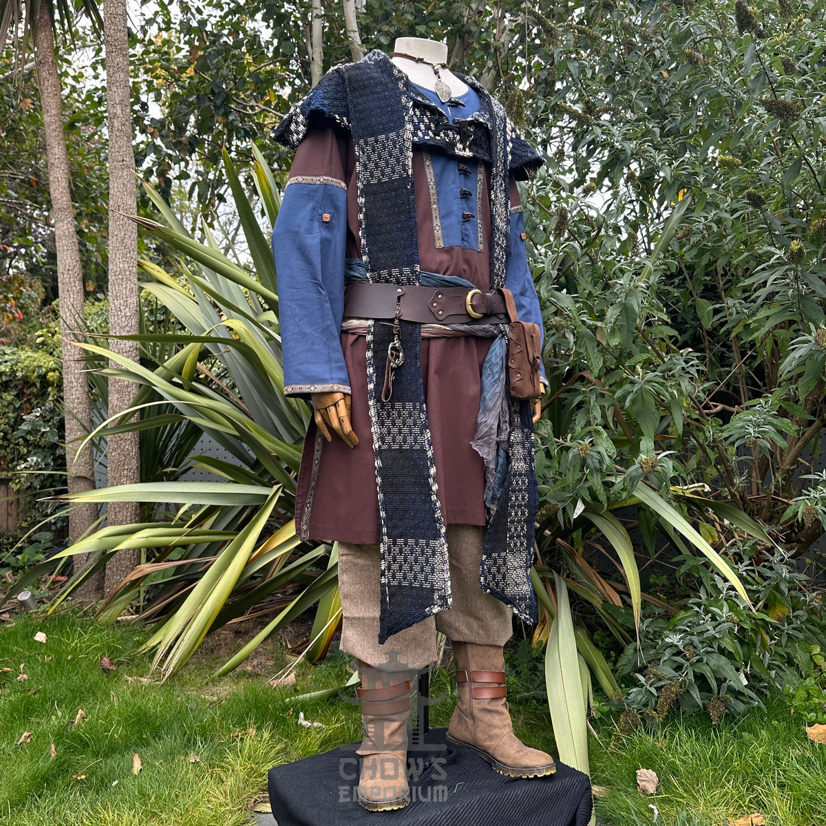 Medieval LARP outfit side view, featuring a brown and blue tunic, hood, trousers, and sash.