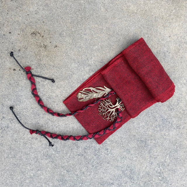 Red herringbone sash with feather brooch, flat lay for LARP.