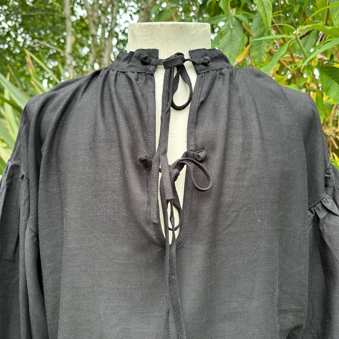 Medieval LARP black shirt close-up with front ties against greenery.