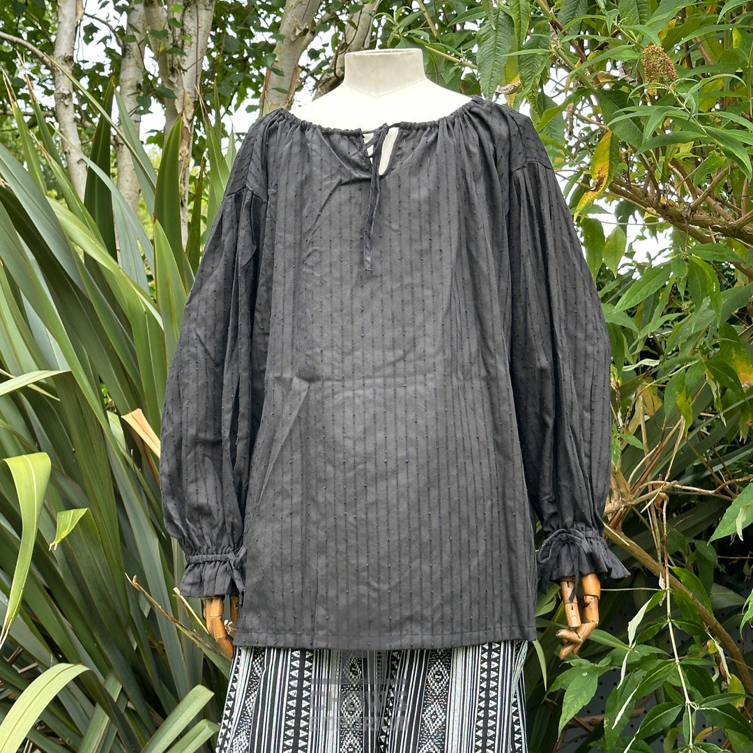 Black medieval shirt with long sleeves, vertical texture, displayed outside.