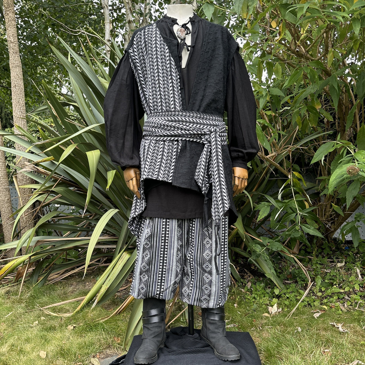 Medieval LARP outfit side view, patterned wrap and black boots.