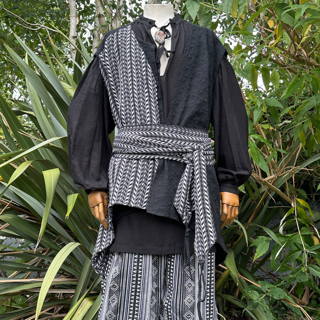 Medieval-style LARP set with patterned sash in a lush garden scene.