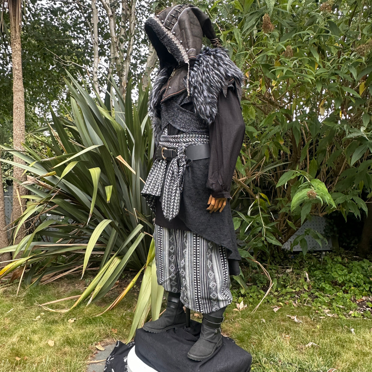 Medieval LARP costume side view, includes faux leather hood, black and white waistcoat with.