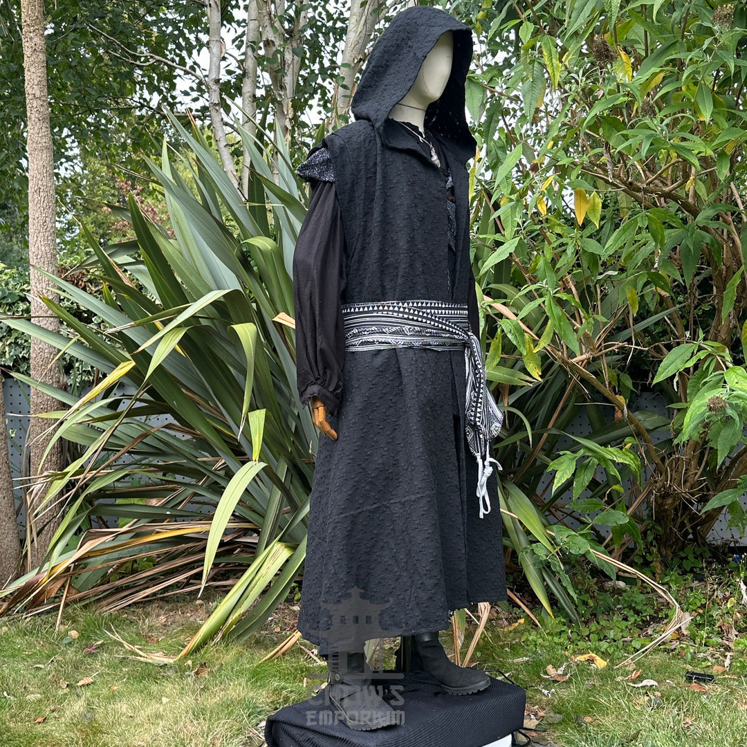 Side view of medieval LARP costume with hooded waistcoat and patterned sash.