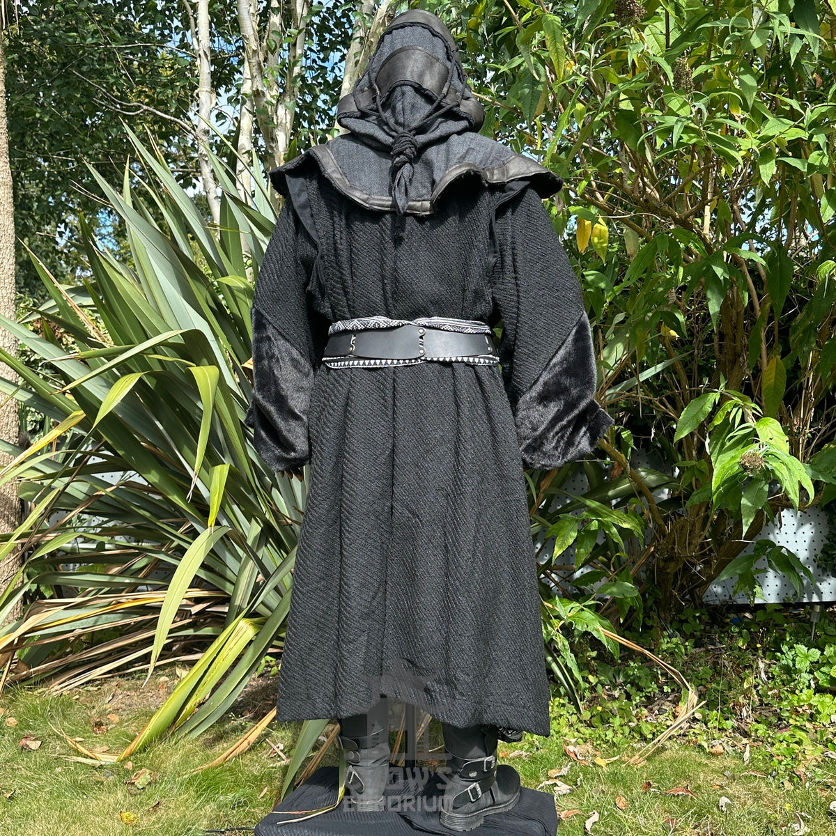Medieval LARP costume back view, featuring a black robe, hood, arm wraps, belt and sash.
