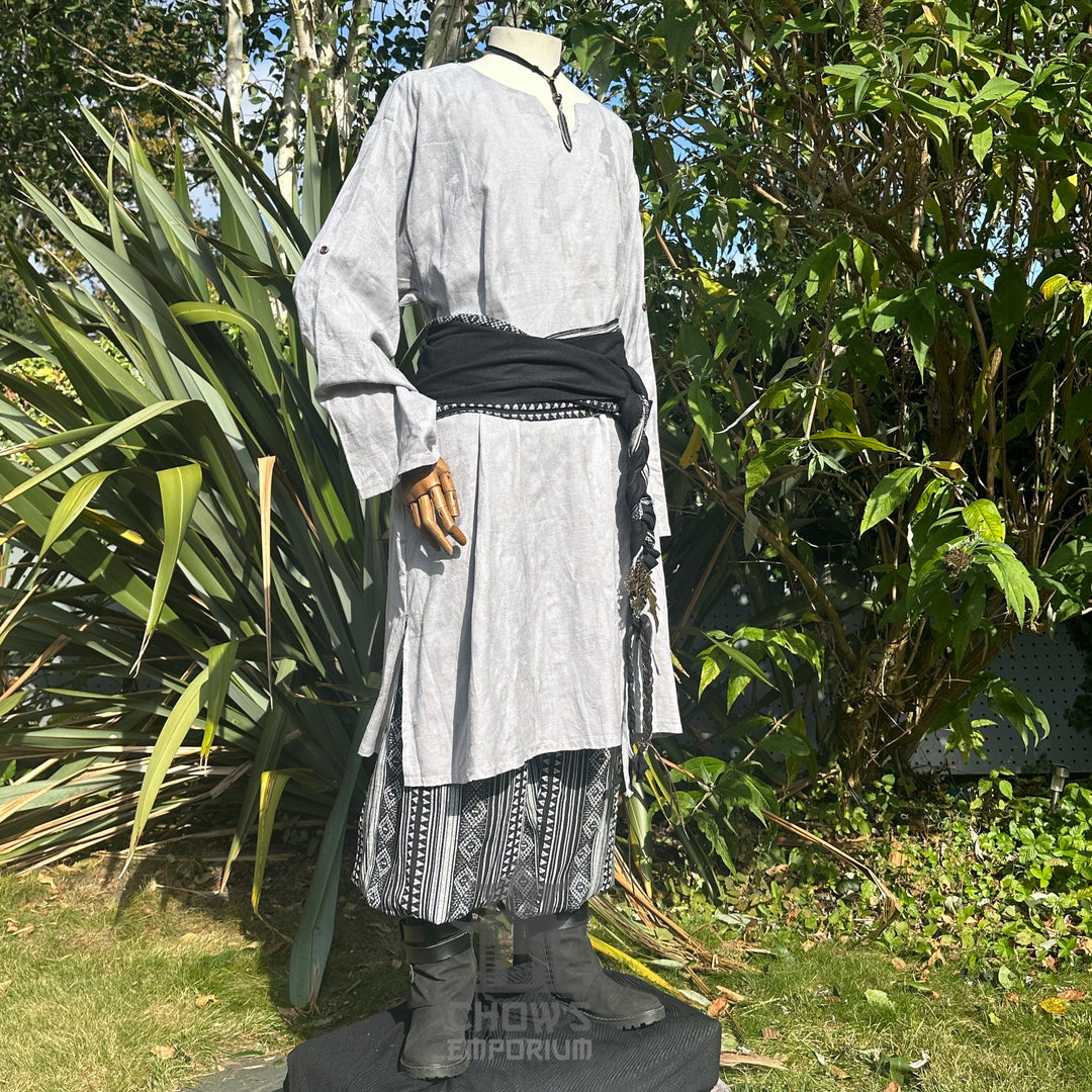 Medieval LARP outfit side view, featuring a grey tunic, black and white trousers and matching sash.
