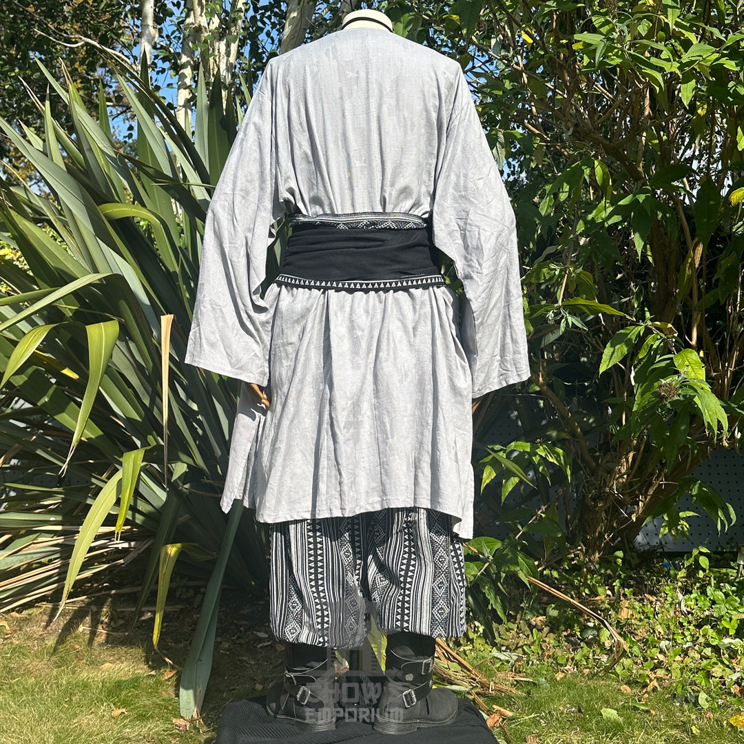 Medieval LARP outfit back view, featuring a grey tunic, black and white trousers and matching sash.