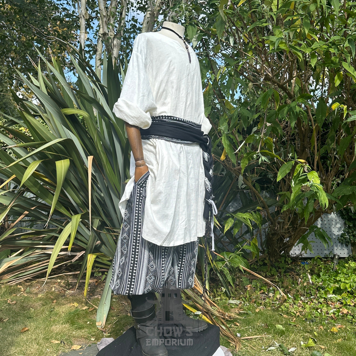 Medieval LARP outfit side view, featuring a white tunic, black and white trousers and matching sash.