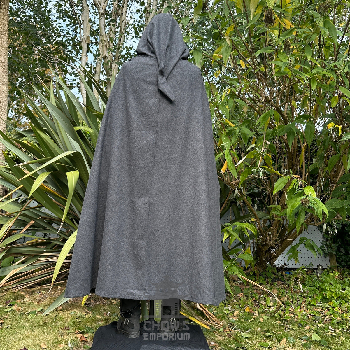 Rear view of LARP cloak and boots amidst leafy greenery.