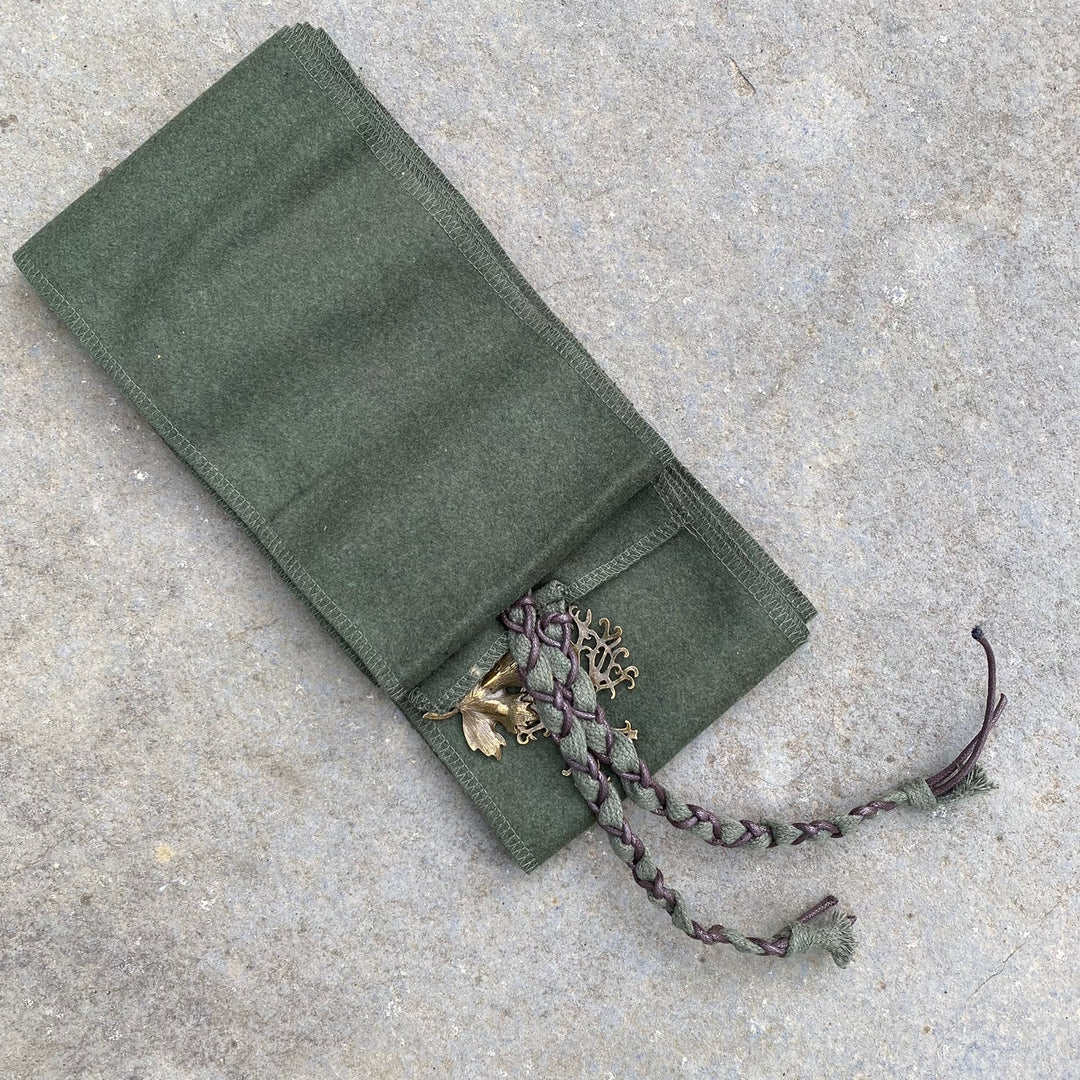 Green medieval LARP wrap with woven trim and bronze embellishments on stone surface.