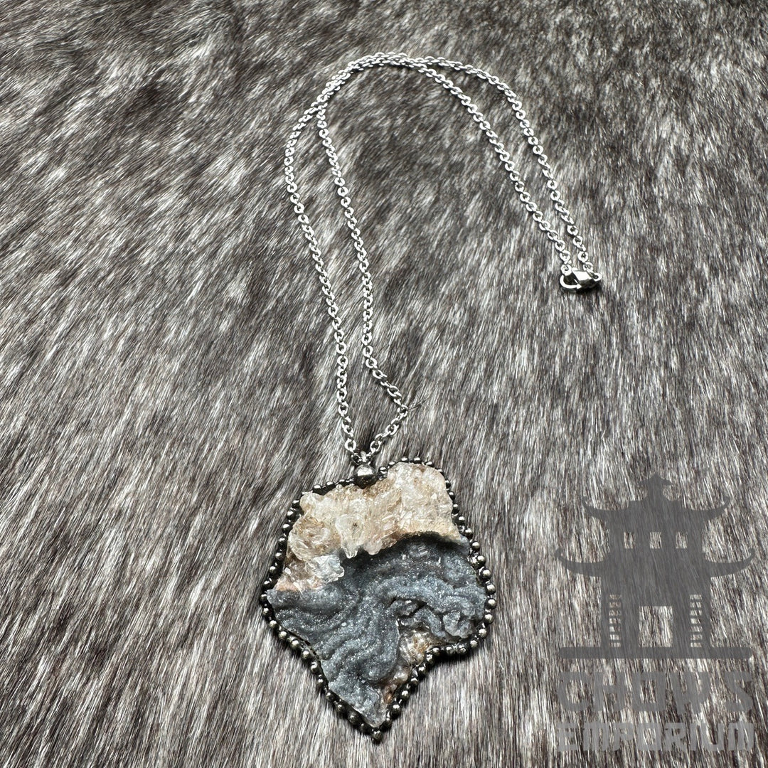 Silver chain necklace with a rough stone pendant on a textured fur background.