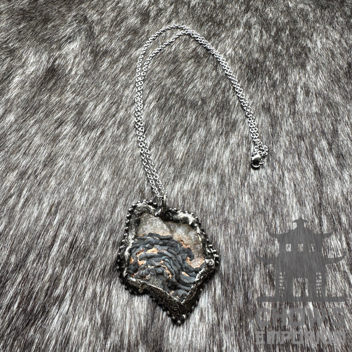 Silver necklace with geode pendant on a textured fur background, medieval LARP style.