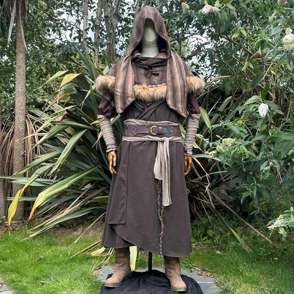 Forest alchemist costume with fur trim, displayed amidst lush greenery for LARP.