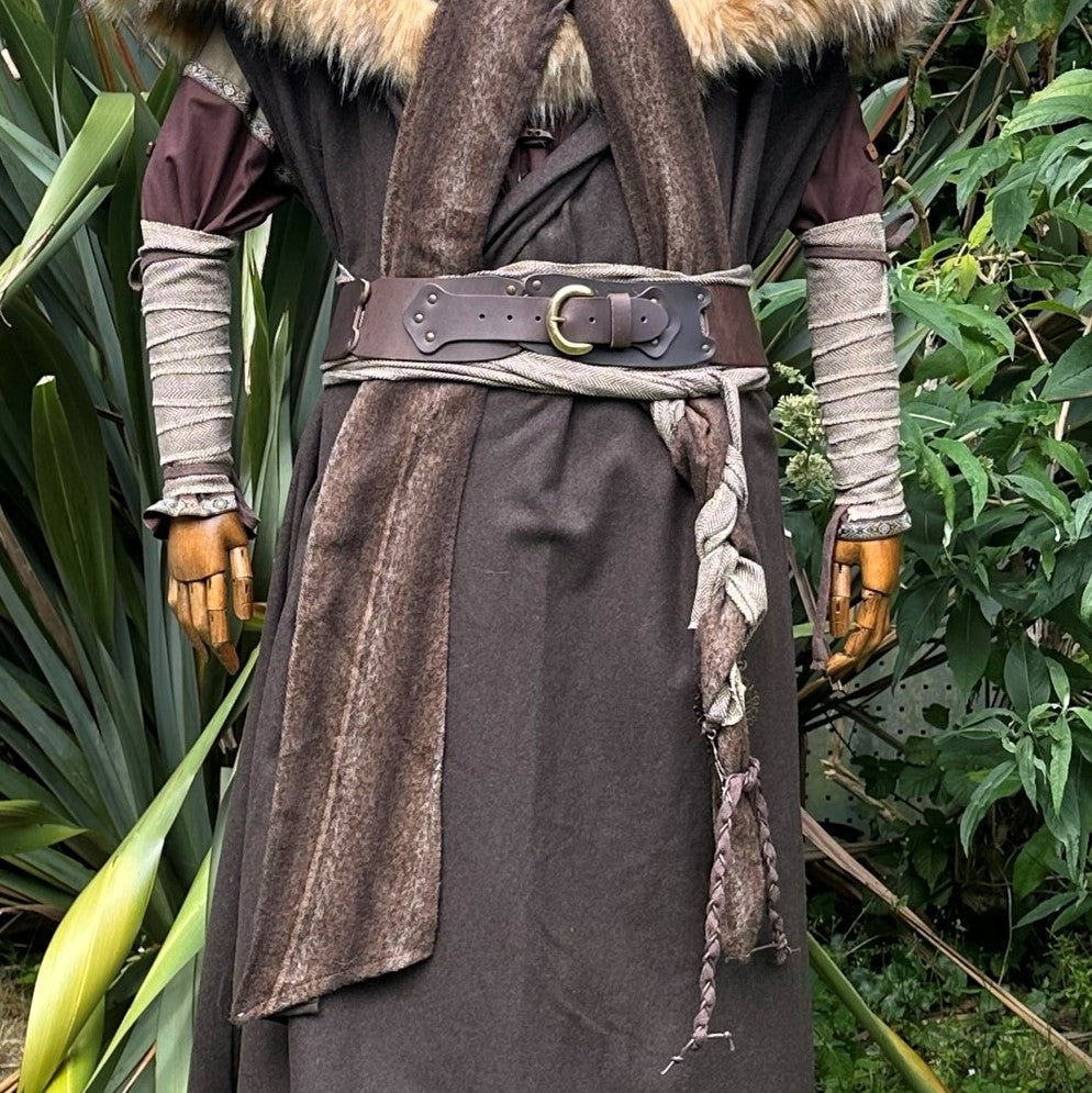 Rear view of medieval LARP outfit; fur-lined cloak, braided sash and arm wraps.