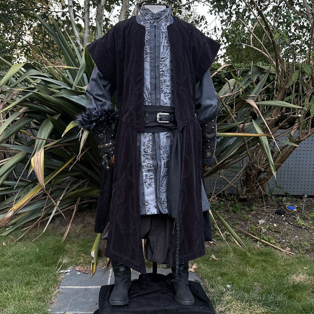 Front view of black medieval waistcoat showing flowing panels and suede-effect fabric texture.
