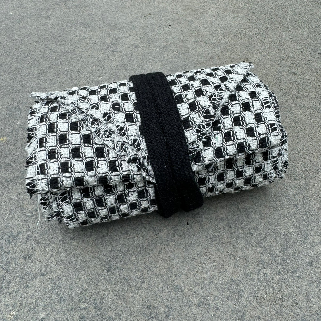 Black and white checkered wool leg wraps for medieval LARP, folded neatly.