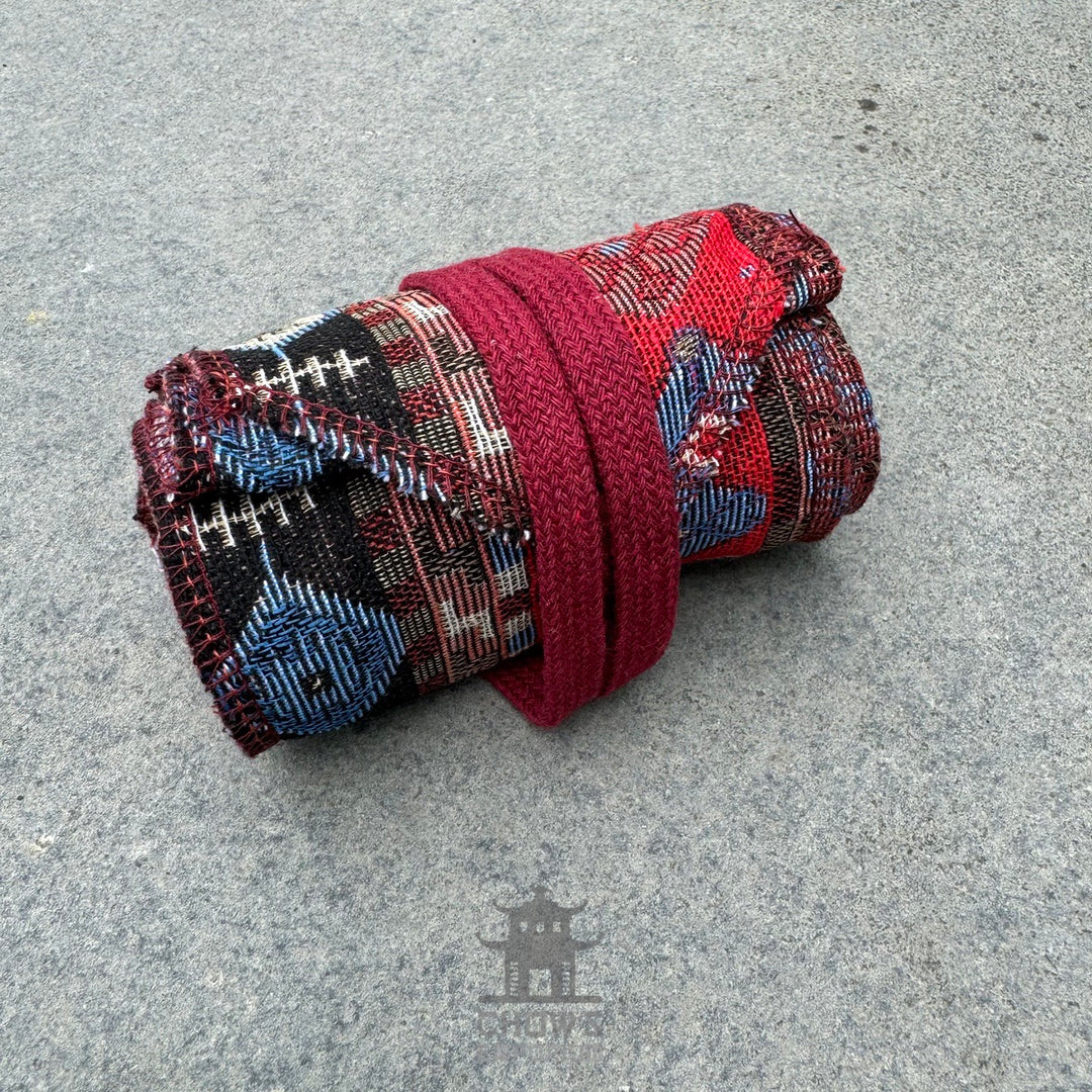 Rolled red Aztec pattern pirate sash for LARP on grey background.