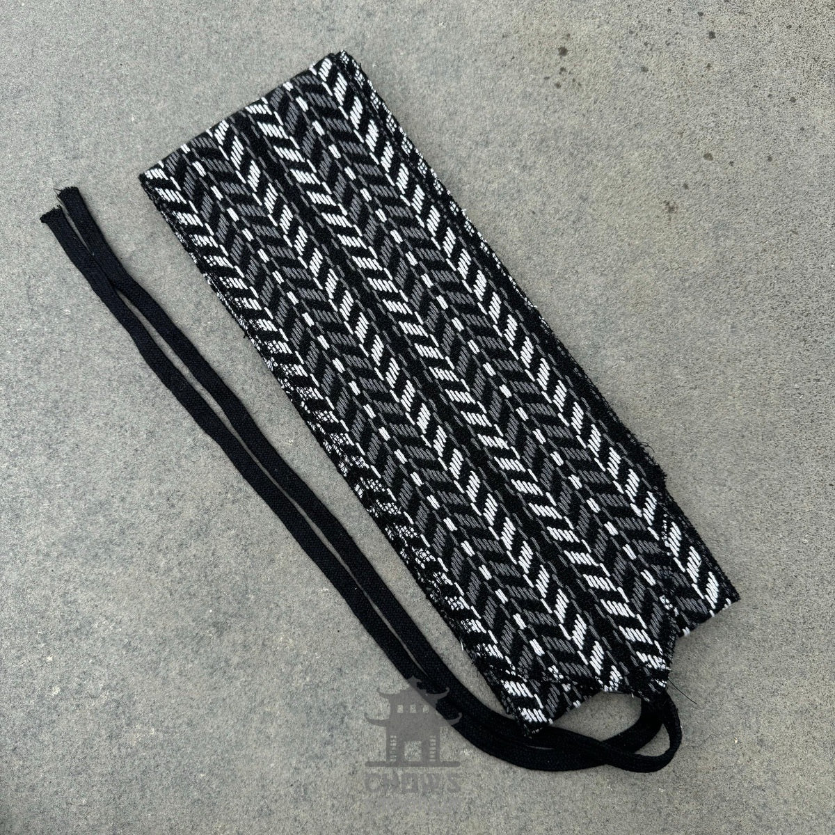 Black and white herringbone sash for LARP, woven textile on flat surface.