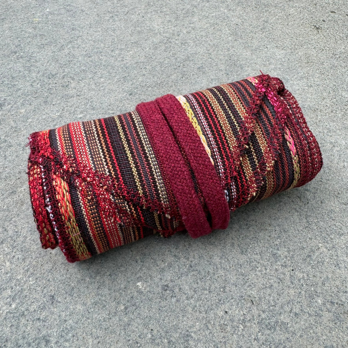 Red striped cotton leg wraps rolled up for LARP.