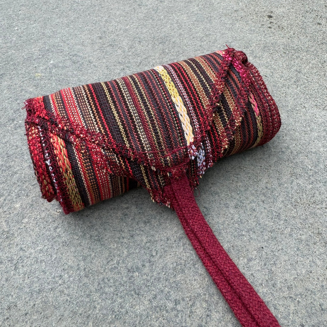 Red striped cotton leg wraps for medieval LARP, rolled and textured.