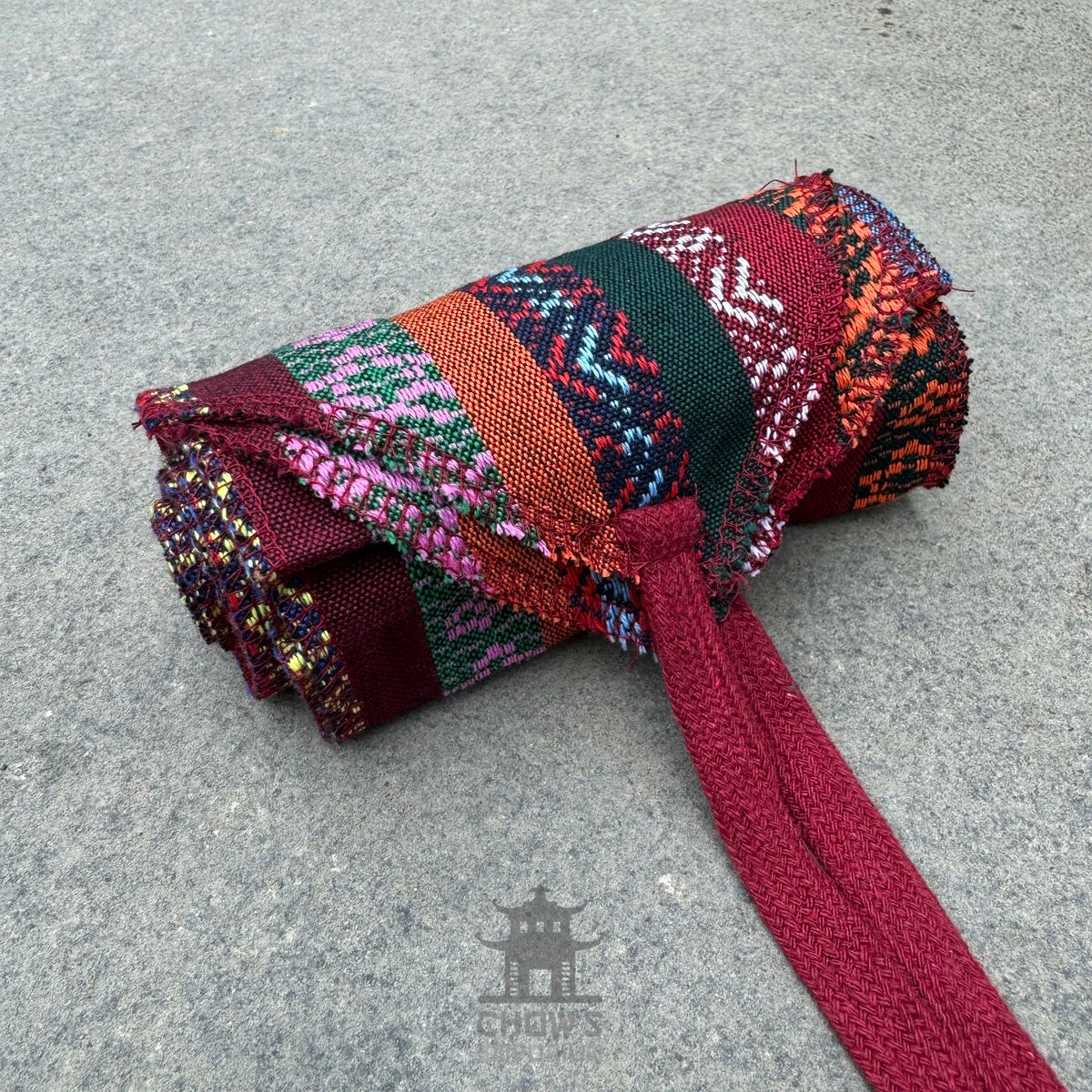 Rolled LARP sash with colorful woven patterns and red fabric tie.