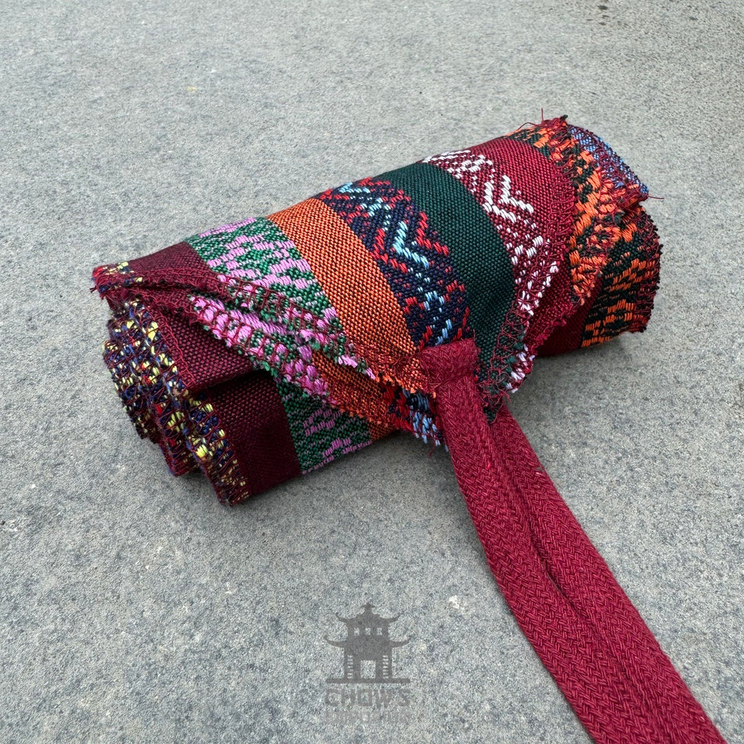 Rolled LARP sash with colorful woven patterns and red fabric tie.