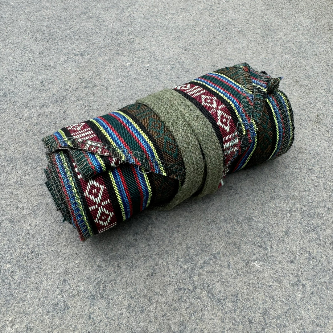 Green striped leg wraps for LARP, rolled on stone surface, woven material.