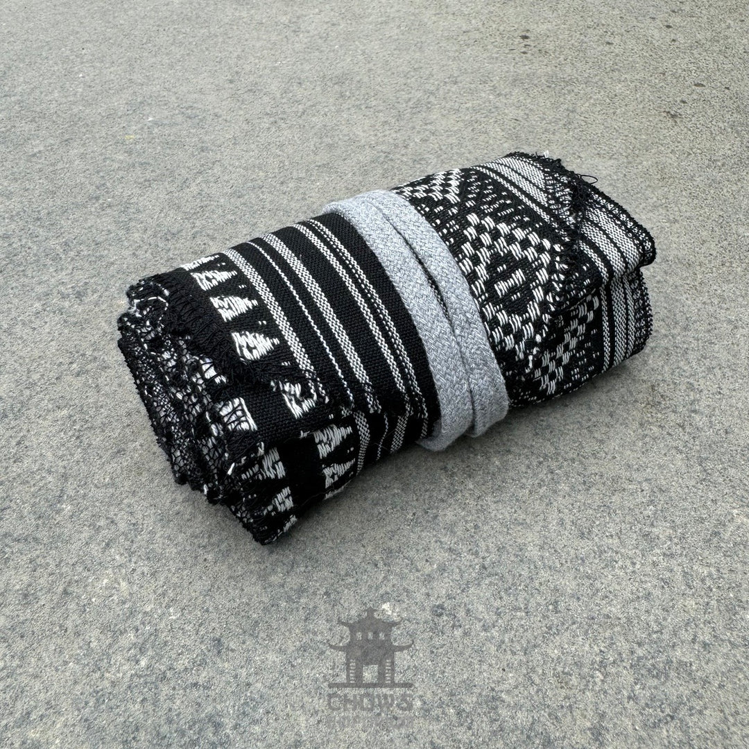 Black and white patterned cotton leg wraps for medieval LARP, rolled.